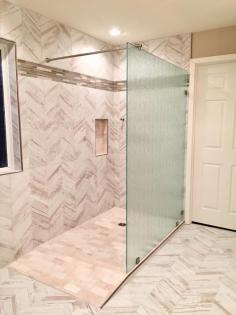handicap accessible glass shower with white and grey herringbone tile 